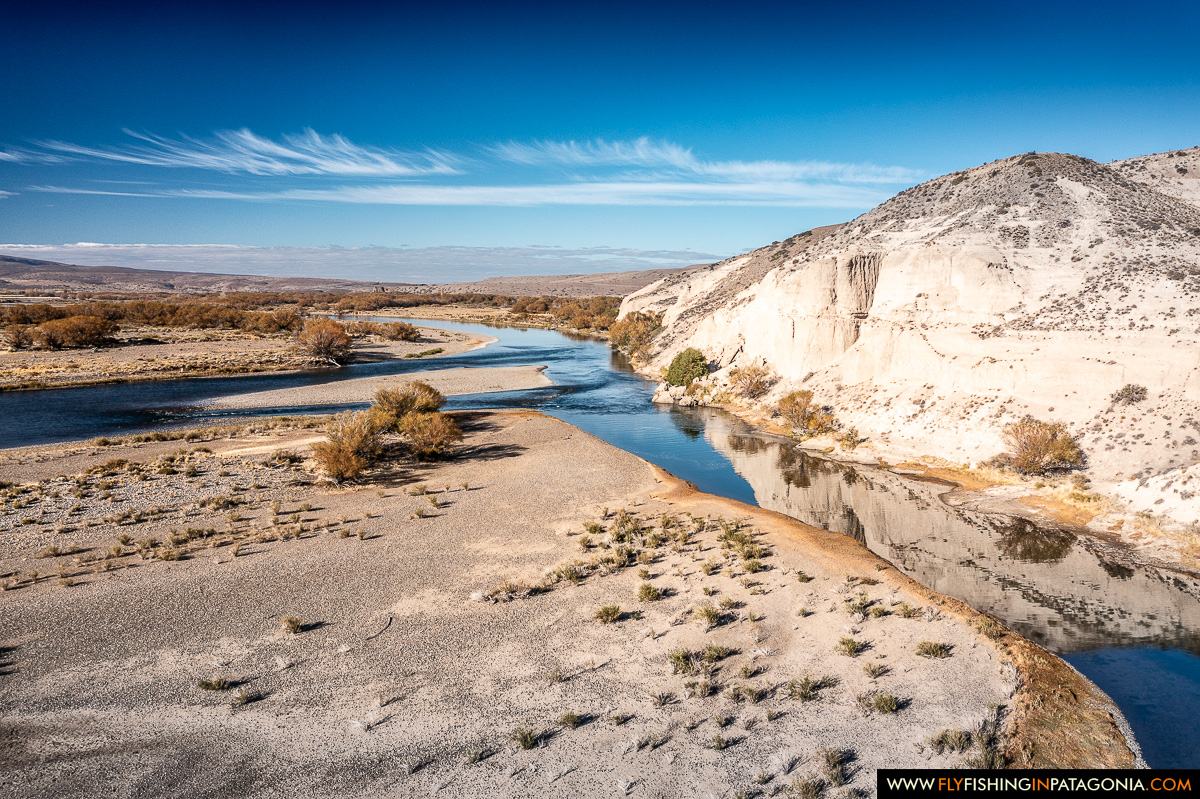 Aerial view of the Collon Cura River flowing beneath pale Patagonian cliffs