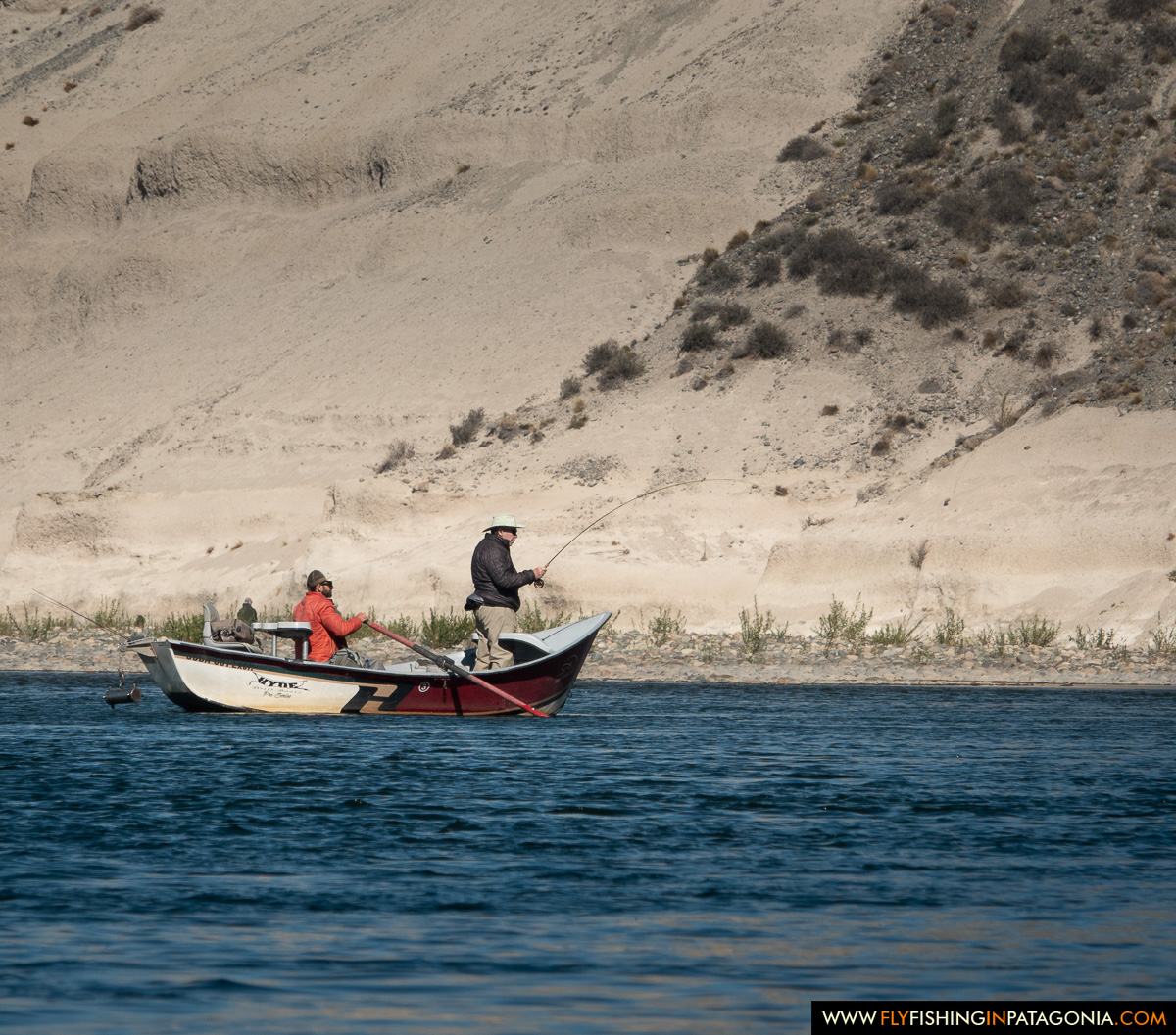 Anglers fly fishing from a drift boat beneath the Collon Cura River cliffs