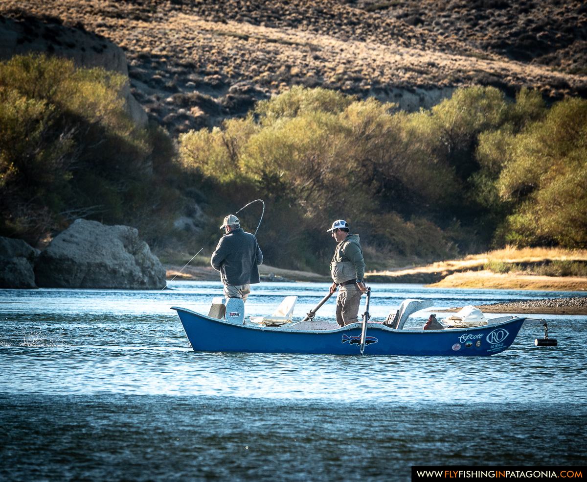 Anglers casting from a drift boat along a willow-lined Collon Cura River bank