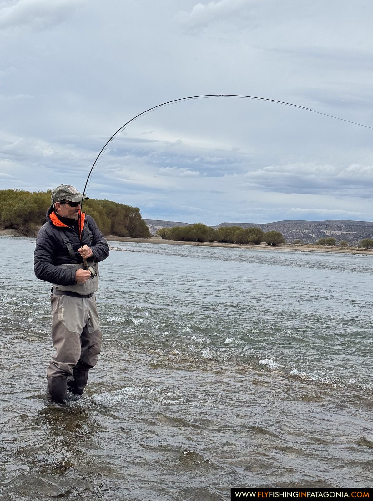 Fly angler fighting a trout while wading the Collon Cura River
