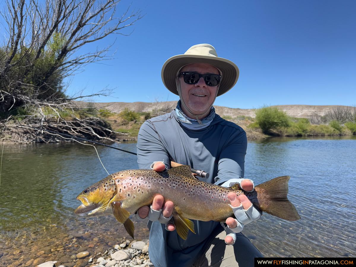 Angler holding a brown trout beside a quiet Collon Cura River channel