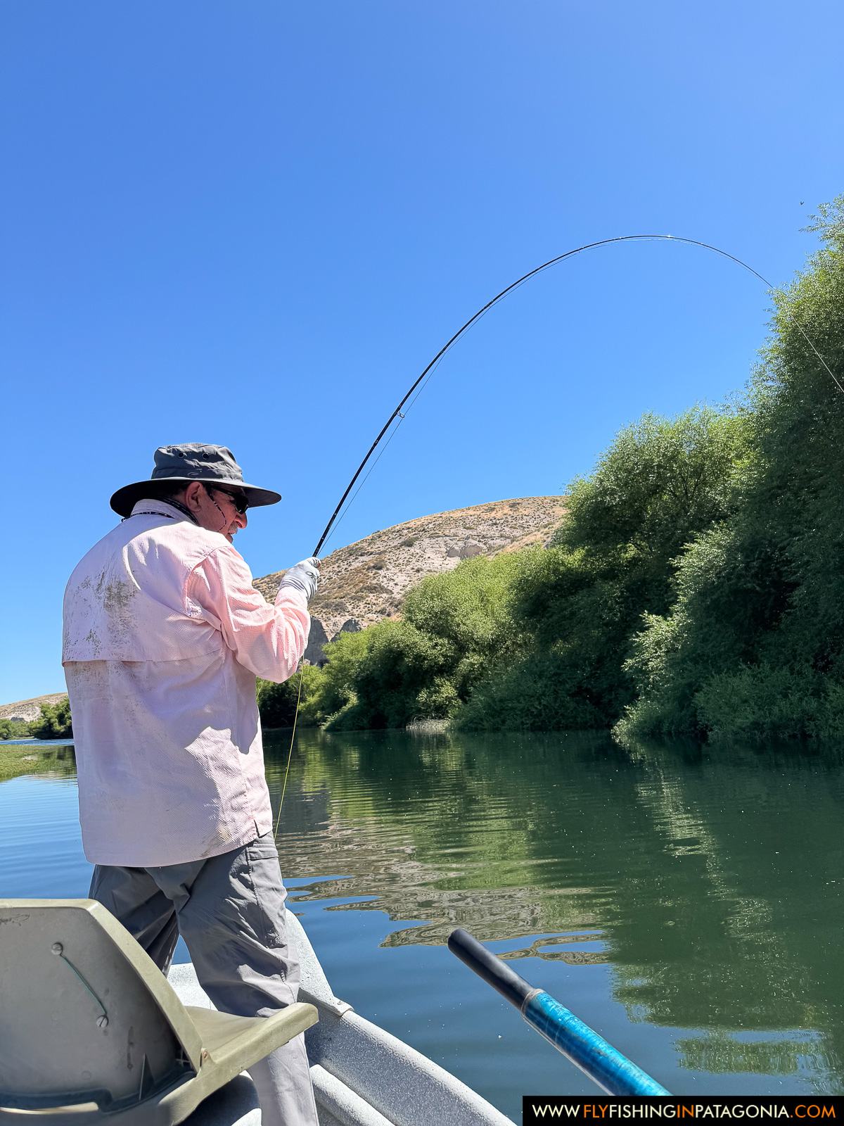 Fly angler fighting a trout from a drift boat on the Collon Cura River