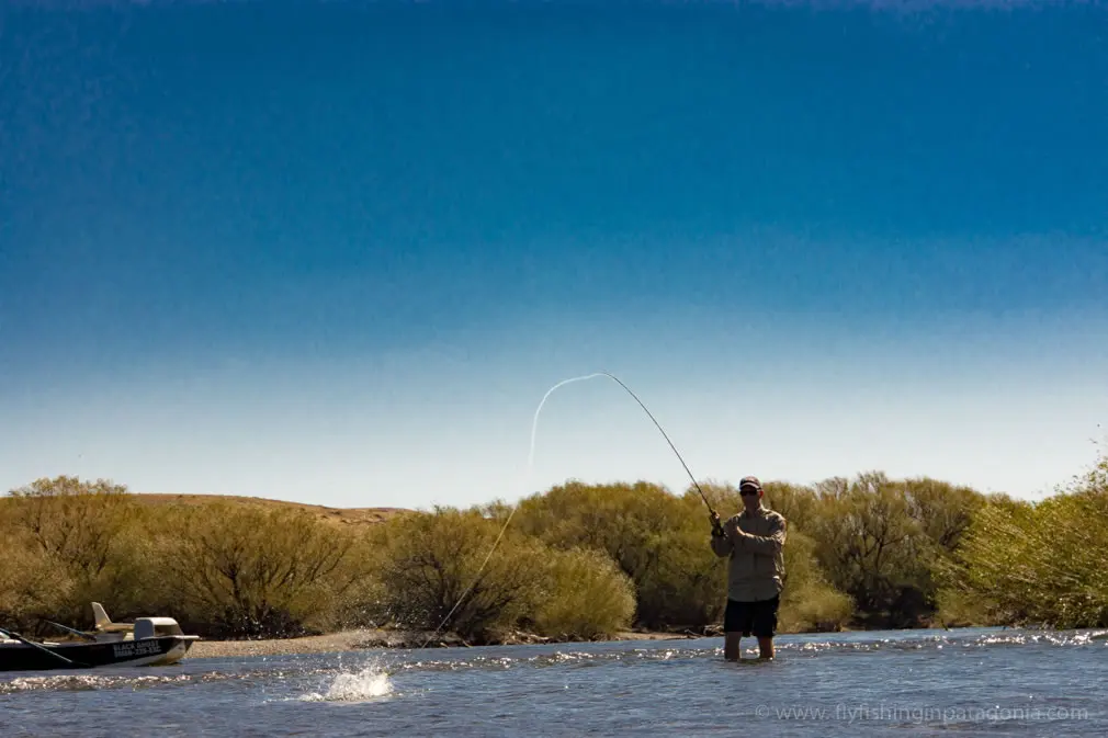 Fly angler fighting a trout from a boat on the Collon Cura River