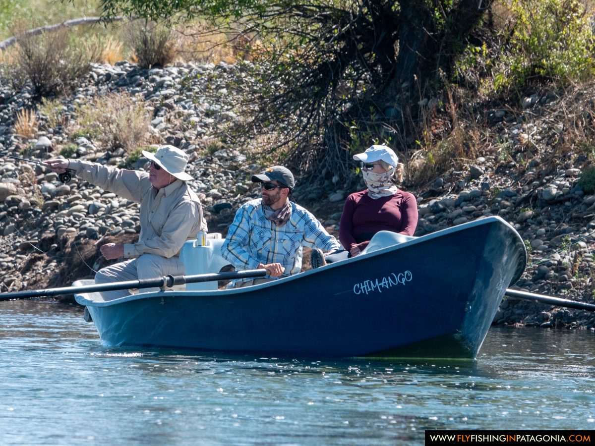 Three anglers fishing a narrow channel of the Collon Cura River from a drift boat