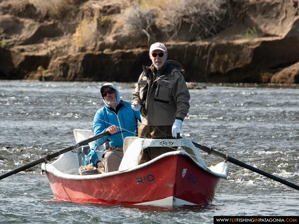 Two anglers fishing from a red drift boat on the Collon Cura River