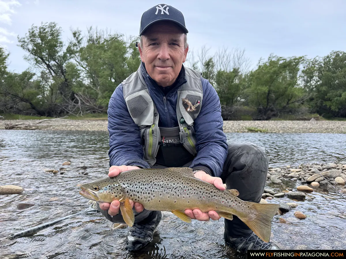 Angler holding a brown trout on a gravel bank of the Collon Cura River