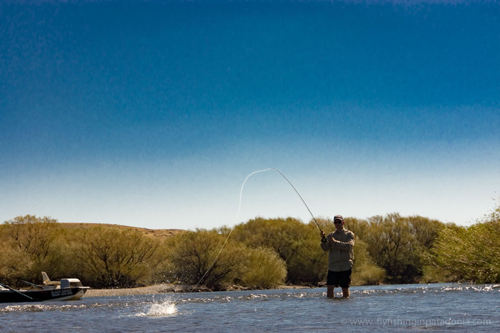 Fly angler fighting a trout from a boat on the Collon Cura River