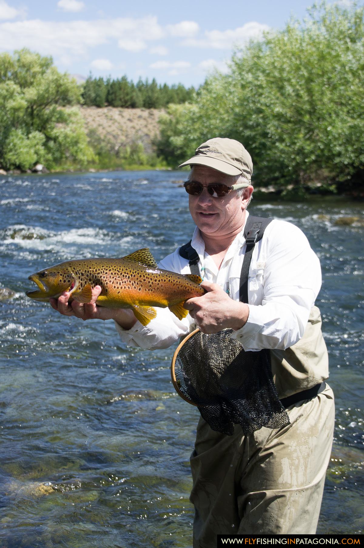 Greg LeMond holding a brown trout below the canyon on the Malleo River