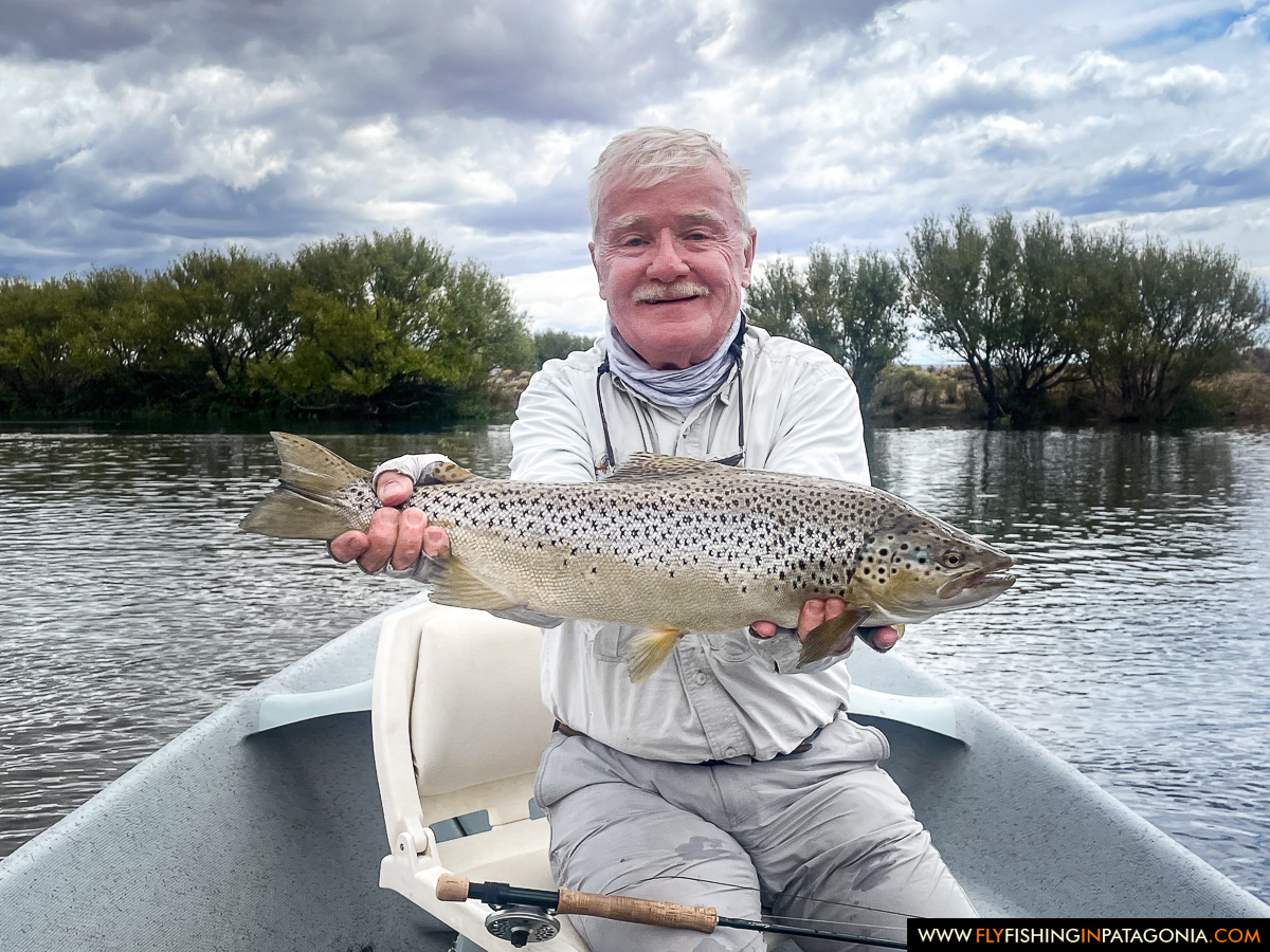 a happy angler with a nice brown trout in the drift boat on the middle limay river