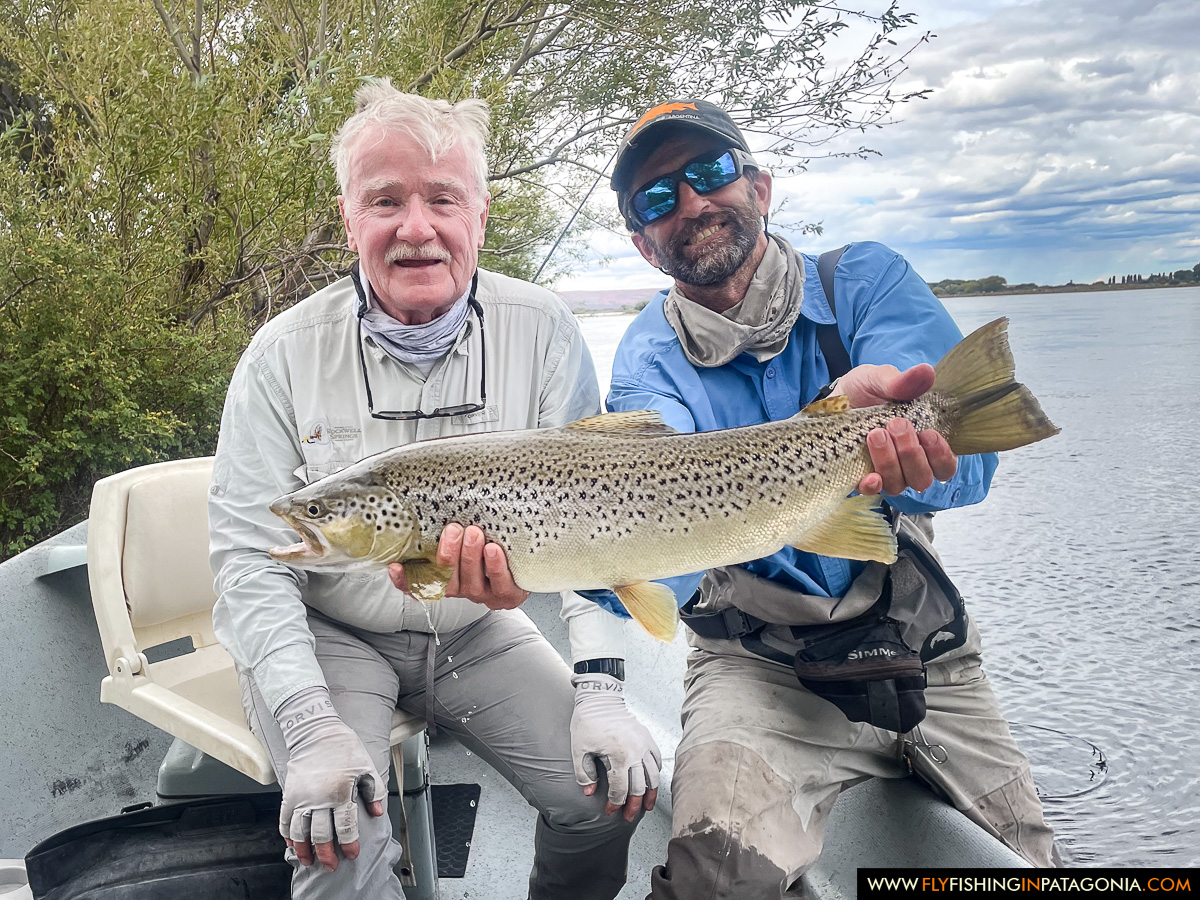 two anglers holding a great brown trout in the boat on the middle limay river