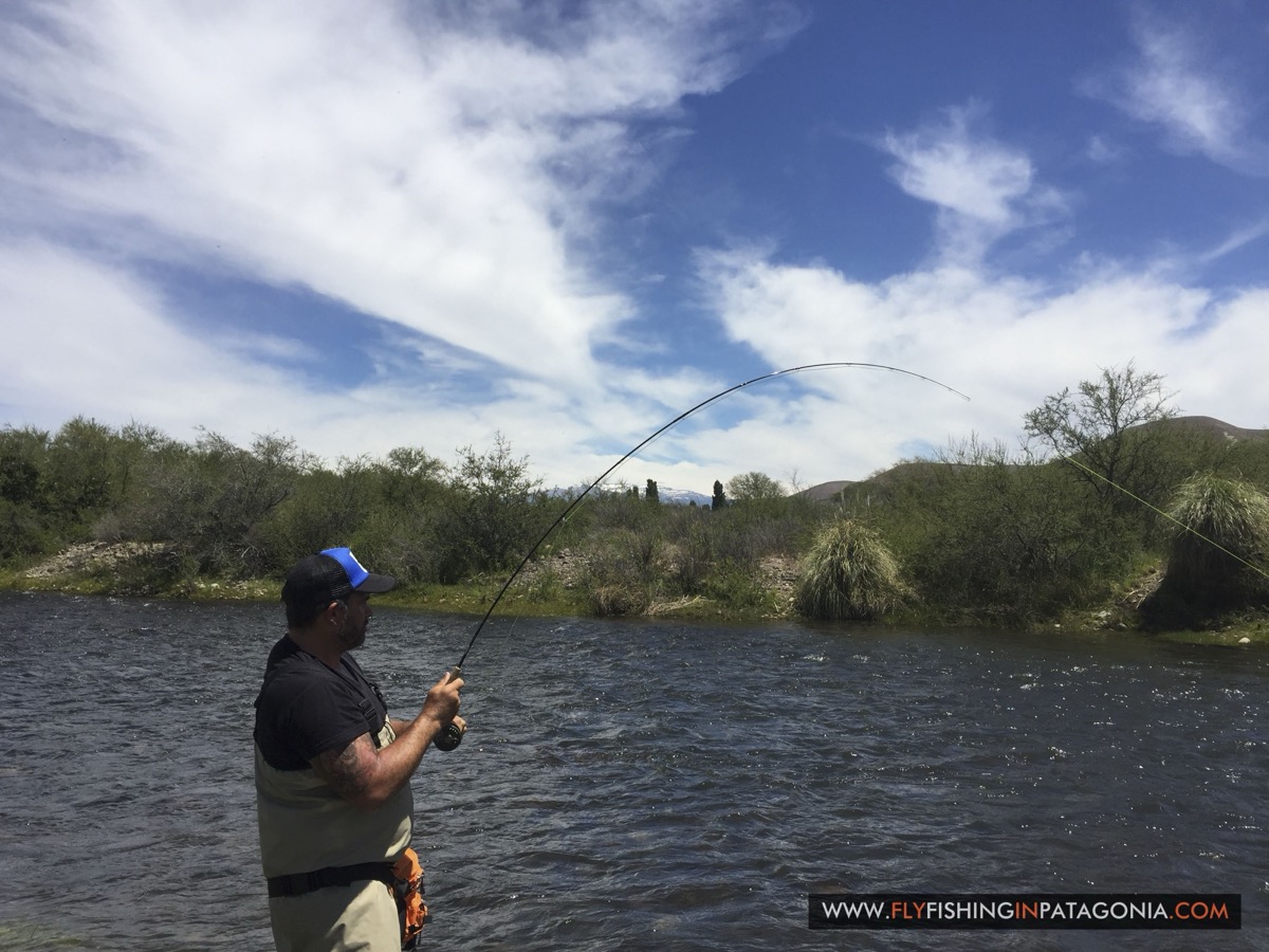 Angler fighting a fish with a bent rod on the Quemquemtreu stream